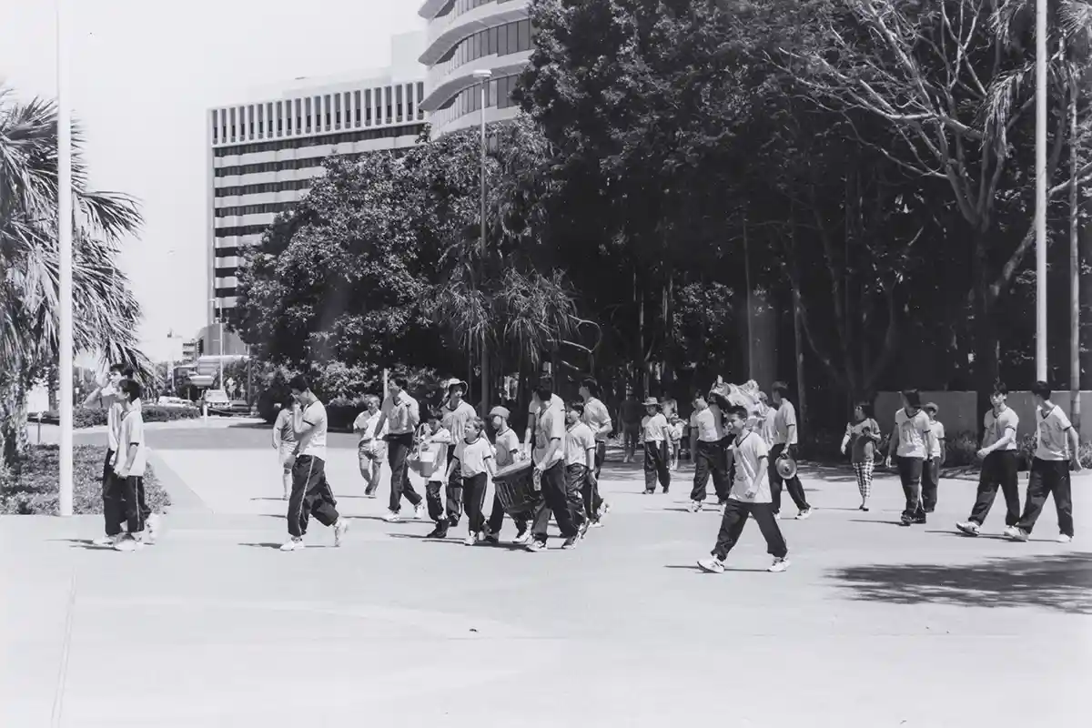 Chinese lion dance troupe crossing the square in front of Parliament House. NT House and Sheraton Hotel above the trees.